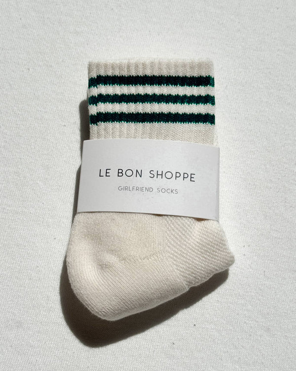 Packaged socks with striped pattern and 'Le Bon Shoppe' label on a light gray background