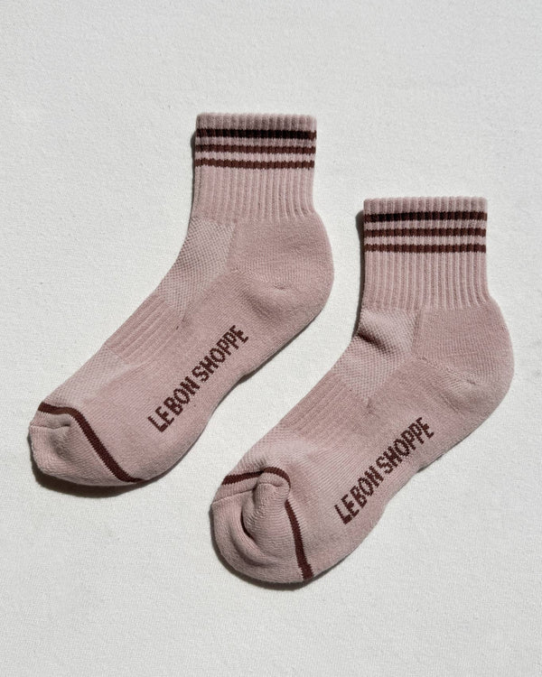 Pair of pink socks with brown stripes and 'Le Bon Shoppe' branding on a light gray background