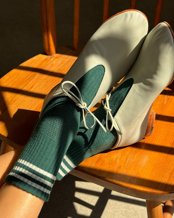 White sneakers with green socks on a wooden chair