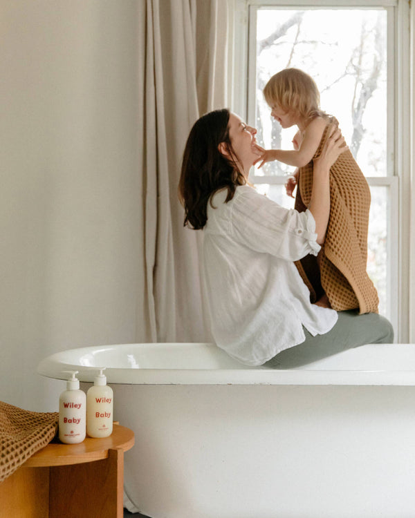 Woman and child in a bathroom with a bathtub and window in the background