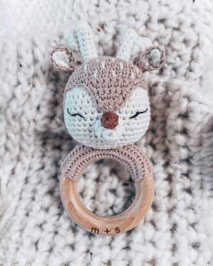Crocheted fox rattle with wooden ring on a textured surface