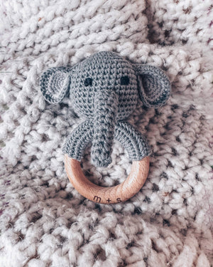 Crocheted elephant rattle with wooden ring on a textured blanket