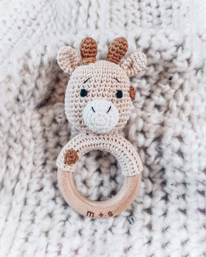 Crocheted giraffe rattle toy on a textured fabric background