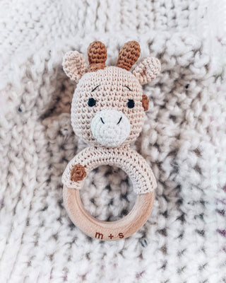 Crocheted giraffe rattle toy on a textured fabric background