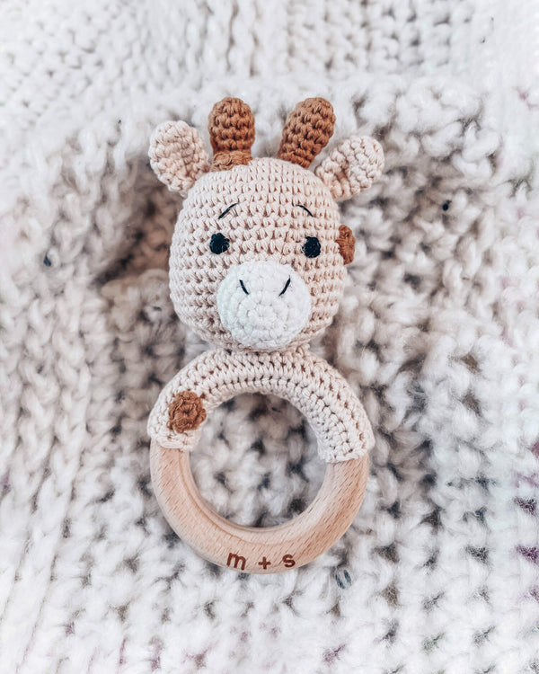 Crocheted giraffe rattle toy on a textured fabric background