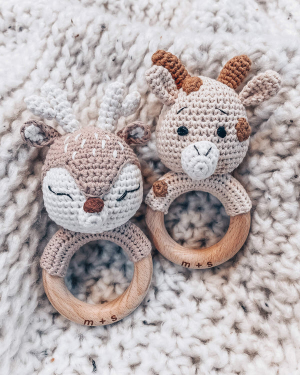 A deer and giraffe crocheted animal rattle toys on a soft, textured surface