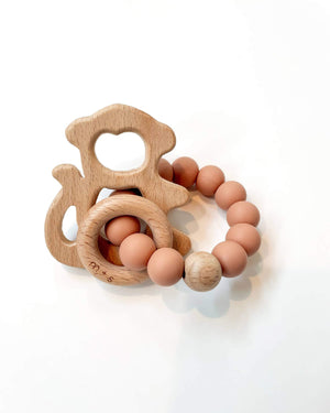 Wooden teething ring with a monkey cut-out and peach silicone beads on a white background
