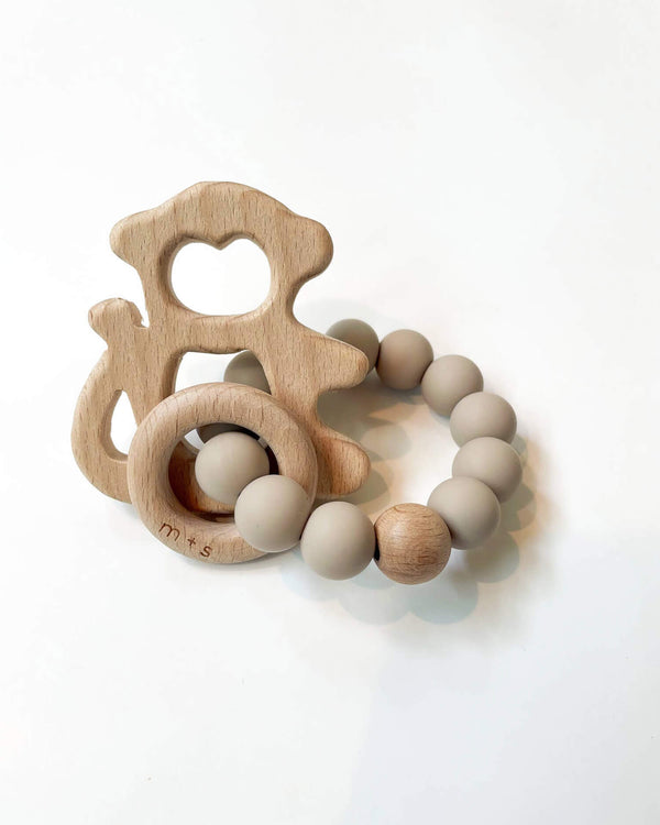 Wooden teething ring with a monkey cut-out and tan silicone beads on a white background