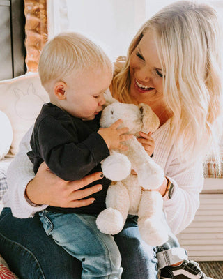 Woman holding a child holding a plush stuffed puppy in a cozy indoor setting