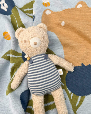 Teddy bear in a striped outfit on a patterned knit blanket
