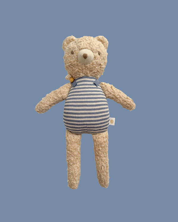 Teddy bear wearing a striped onesie on a blue background