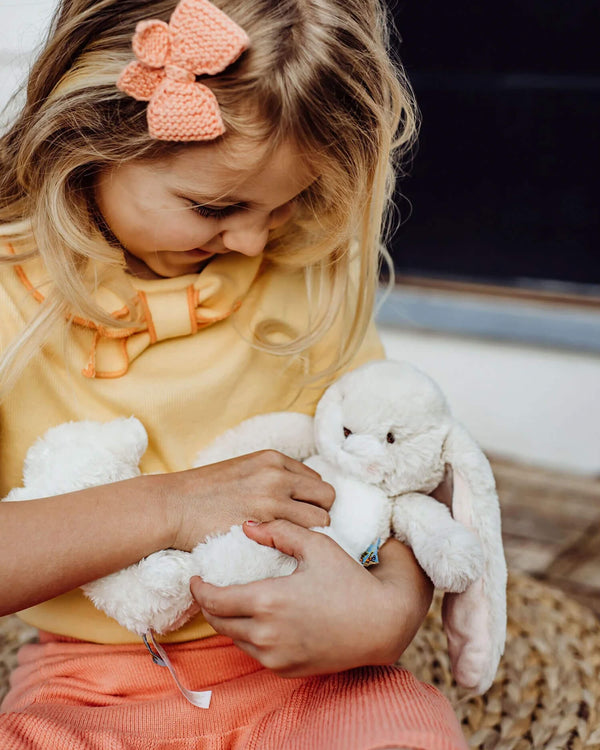 Child holding a plush bunny toy with a blurred background