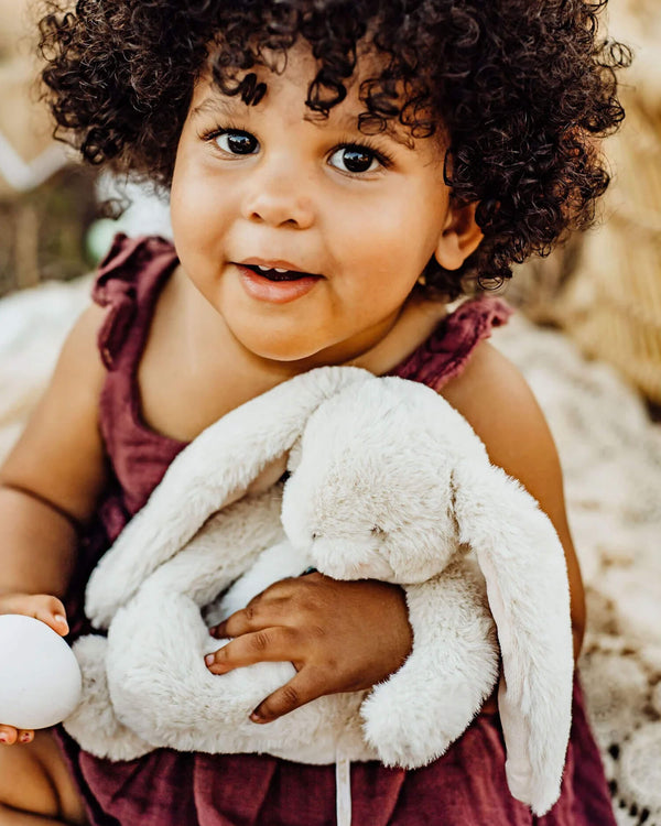 Child holding a plush bunny toy outdoors