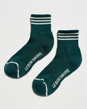 Green socks with white stripes and 'Le Bon Shoppe' branding on a light gray background