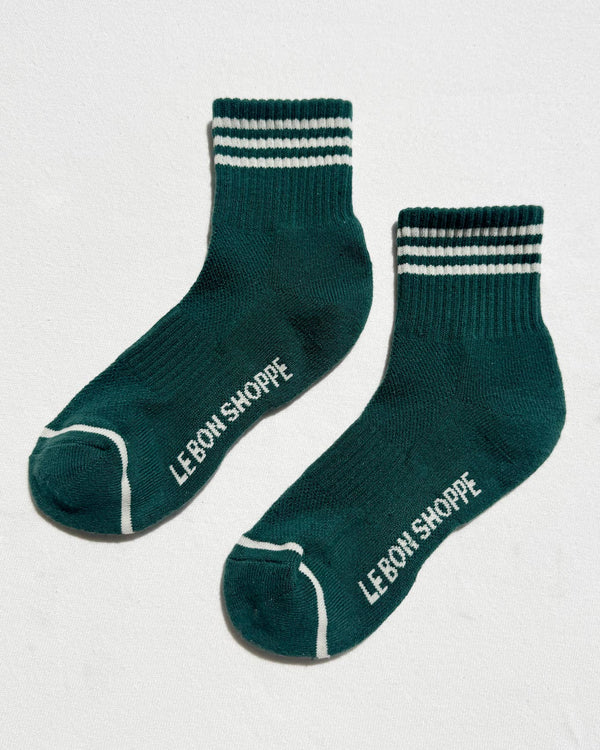 Green socks with white stripes and 'Le Bon Shoppe' branding on a light gray background