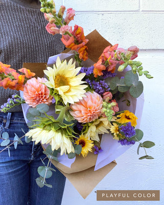 Classic bouquet in a playful color palette with dahlias, sunflowers, snapdragons, and bright seasonal blooms.
