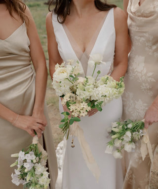 Bride and bridesmaids holding airy white and green wedding bouquets designed by Landfall Floral Co.