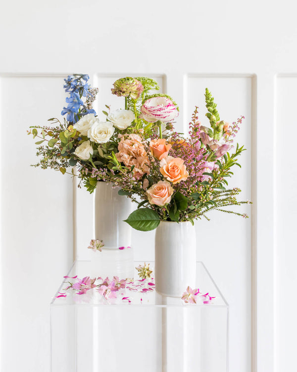 Two Darling Arrangements designed in different colored palettes and with natural garden-style flowers in soft pinks, white, and fresh greenery.