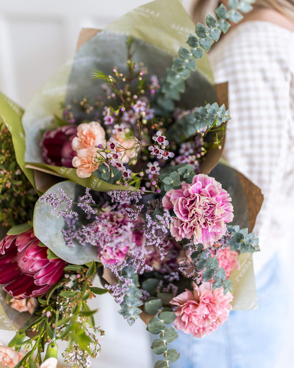 Close-up view of the Darling Bouquet showcasing pink carnations, lilac-toned filler flowers, and eucalyptus with soft, delicate movement.