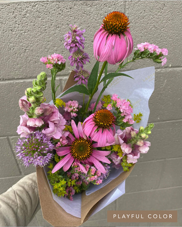 Darling Bouquet in the Playful Color palette featuring bright pink coneflowers, snapdragons, and textural stems in a kraft paper wrap.