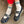 Person wearing navy shoes with buckles and white socks with green stripes on a concrete floor.