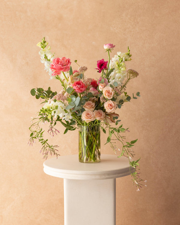 Mother's Day Classic Arrangement displayed on a pedestal — full, garden-style flower arrangement in a tall glass vase, Landfall Floral Co.