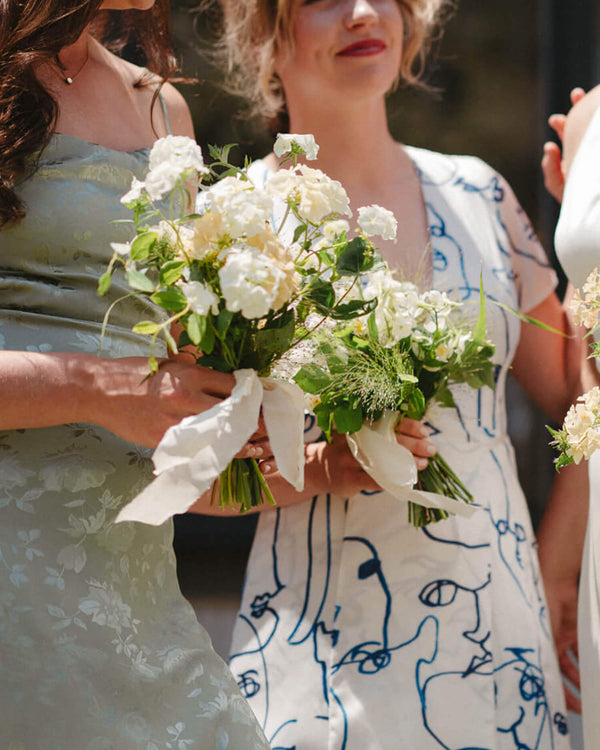 Contemporary white posy bouquets for bridesmaids, designed with airy seasonal florals and soft natural texture.