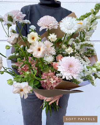 Luxe bouquet in a soft pastel palette with butterfly ranunculus, hydrangea, snapdragons, and textural seasonal blooms.