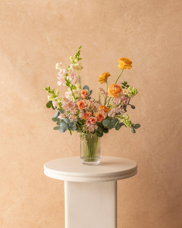 Mother's Day arrangement of snapdragons, ranunculus, and spray roses in a ribbed glass vase — Landfall Floral Co.