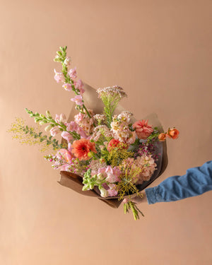 Grand Mother's Day wrapped bouquet in peach, coral, and soft pink — airy garden-style composition wrapped in kraft paper, Landfall Floral Co.