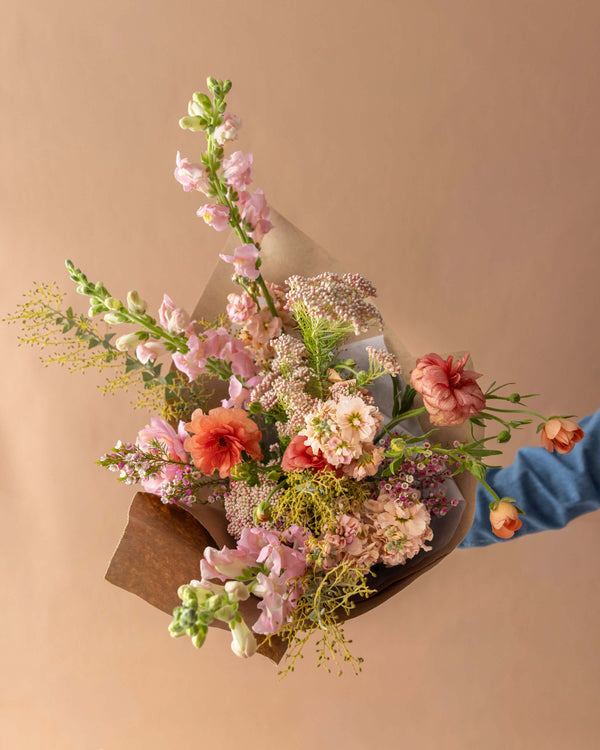 Grand wrapped bouquet for Mother's Day in peach and coral with snapdragons, ranunculus, and wild greenery, Landfall Floral Co. in Edgewater, Denver.