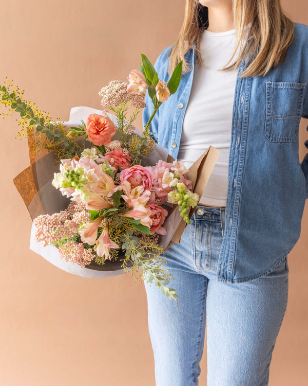 Signature wrapped bouquet for Mother's Day in peach and coral, held for scale — Landfall Floral Co., Edgewater florist.