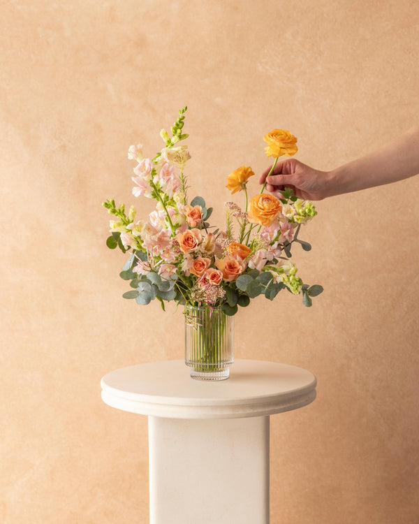 Mother's Day Signature Arrangement — peach, pink, and tangerine flowers in a ribbed glass vase, hand-arranged by Landfall Floral Co. in Edgewater, Denver.