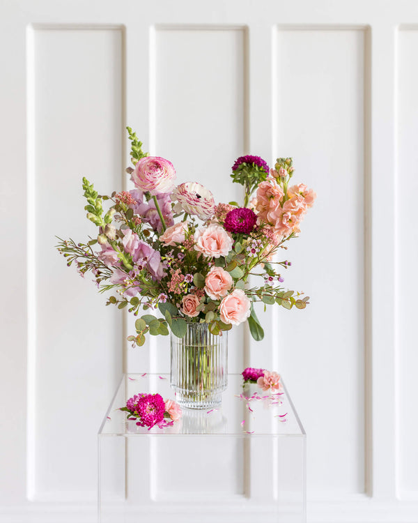 ignature Arrangement in a ribbed-glass vase with soft pastel flowers by Landfall Floral Co.