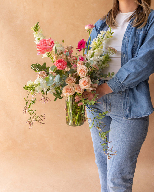 Grand Mother's Day flower arrangement held up for scale — peach spray roses, pink peony tulips, and snapdragons by Landfall Floral Co.