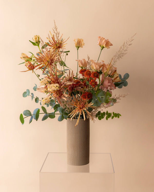 Classic Bouquet arranged in a tall earthenware vase with airy movement and seasonal blooms in Landfall’s natural style.