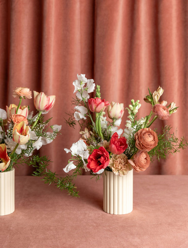Two Love Story Valentine’s Day arrangements side-by-side, showing natural variation in colors and blooms while maintaining the same style and scale.